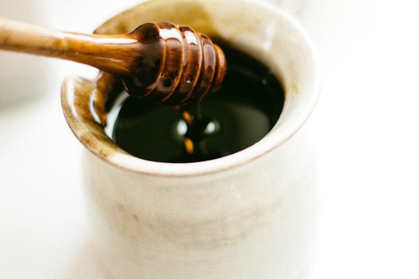 ξύλινο κουτάλι με μέλι και φλιτζάνι τσάι
